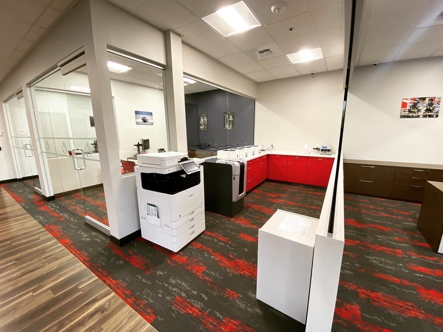 Office interior with a printer, red cabinets, and patterned carpet.