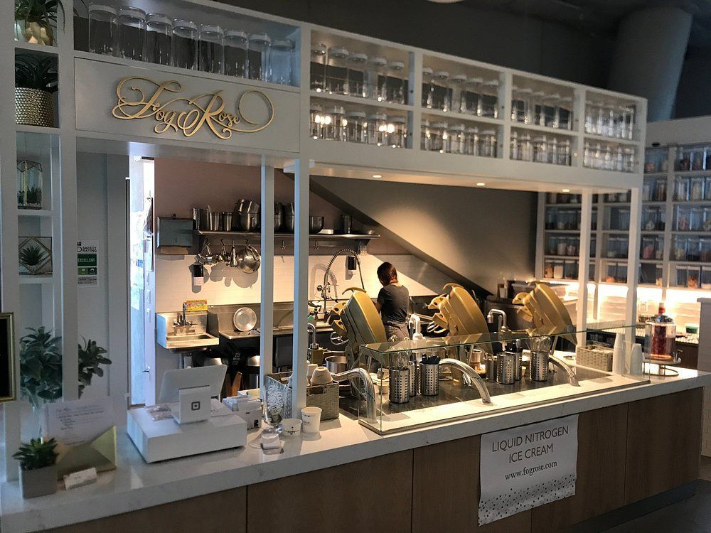 Small café counter with pastries, coffee machines, and glass display in a bright, modern interior