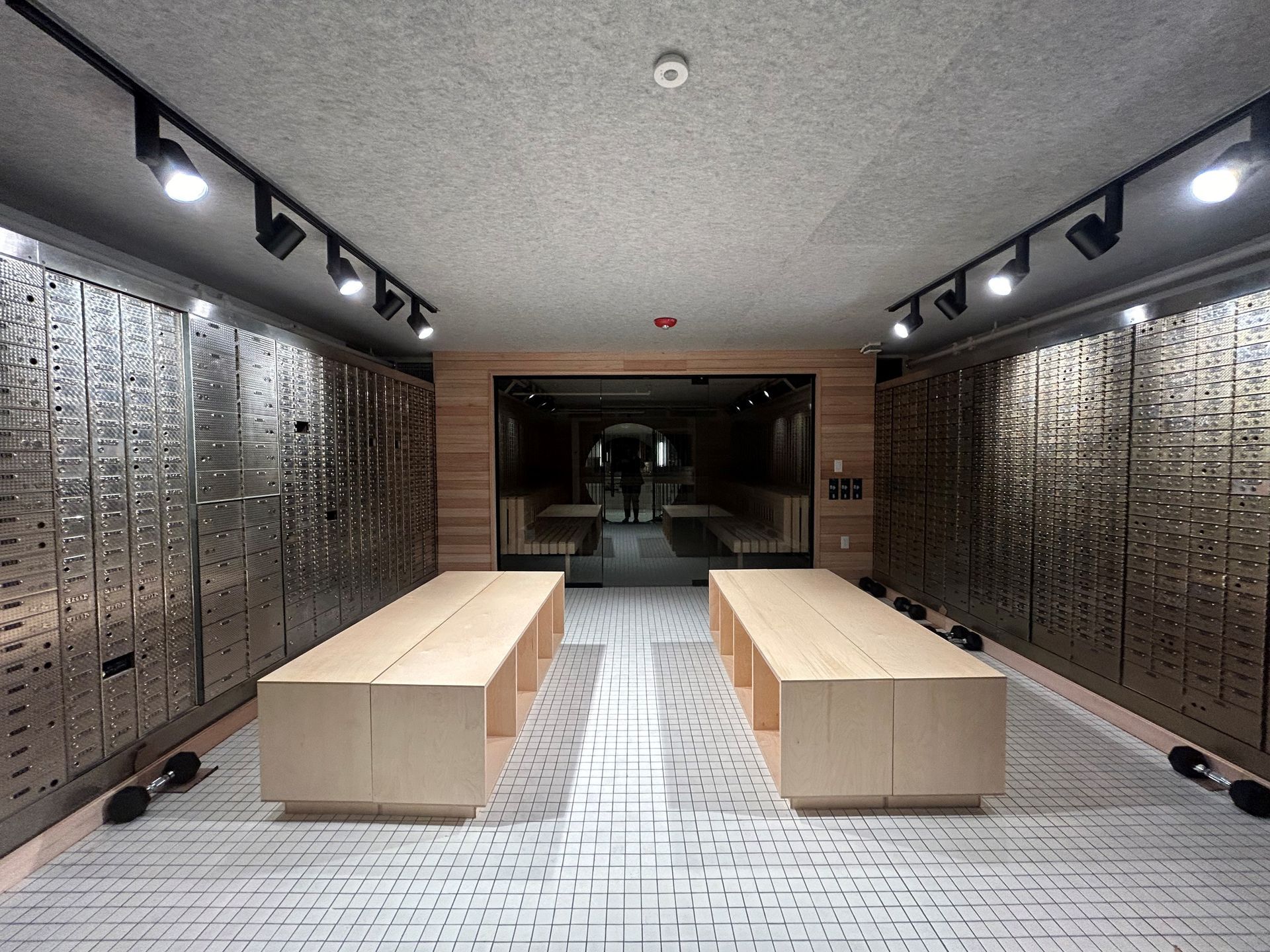 A modern room with display tables, storage lockers, and recessed lighting. A person stands in the doorway.