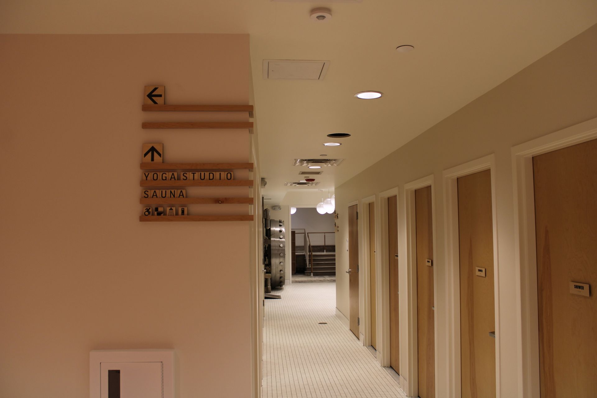 Hallway in a retail store with dressing rooms on the right and a directional sign on the left wall.