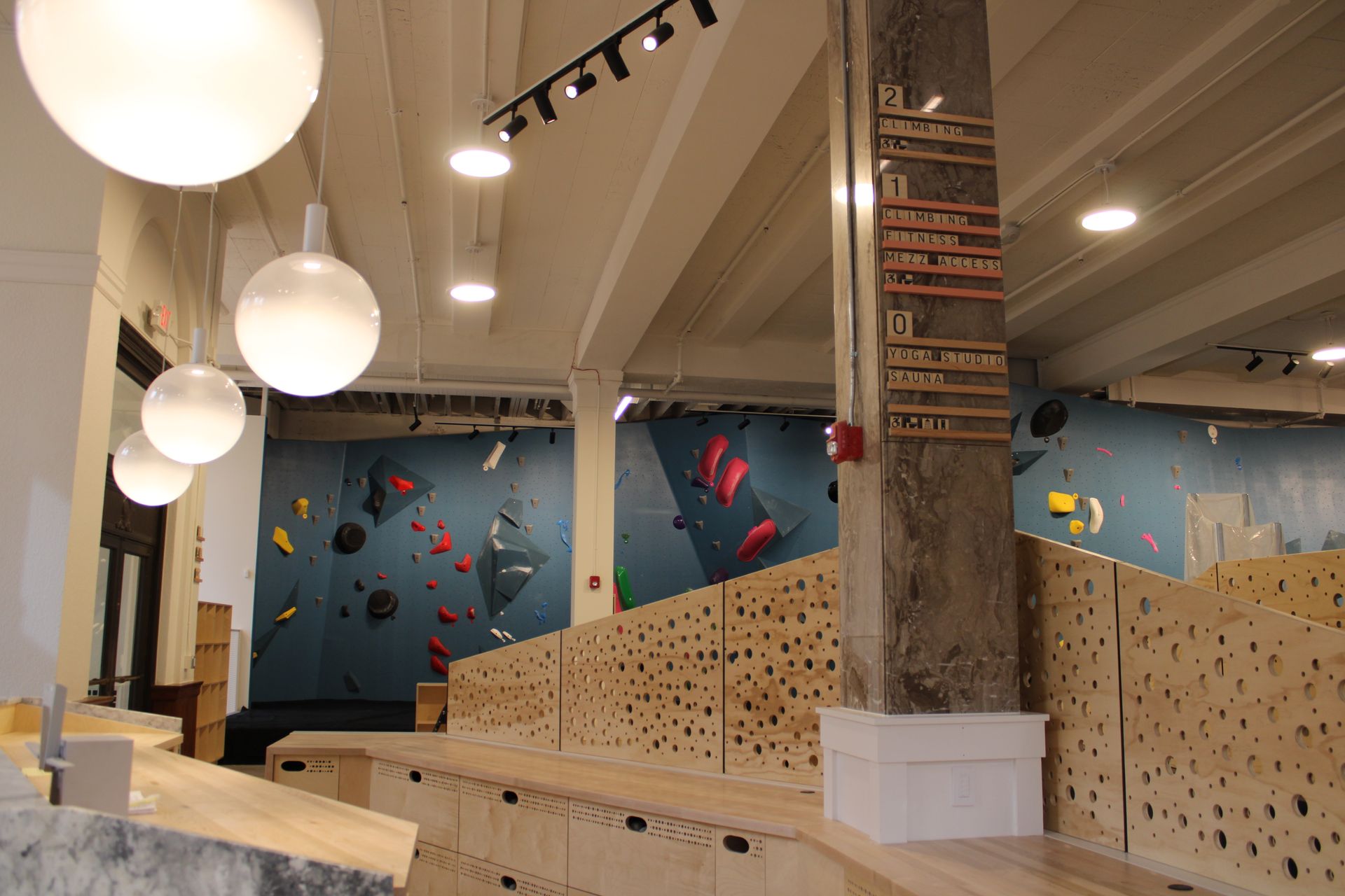 Indoor rock climbing gym with blue walls, wooden features, and hanging lights.