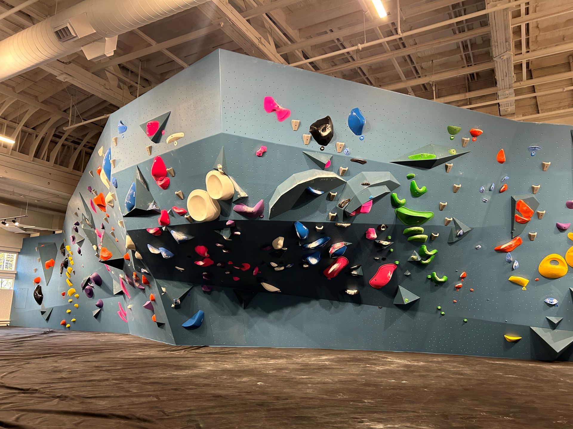 Blue indoor climbing wall with colorful holds.