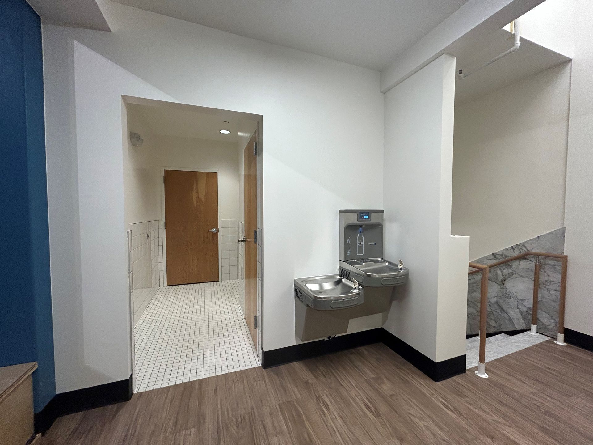 Hallway with water fountain, door to restroom, and stairs.