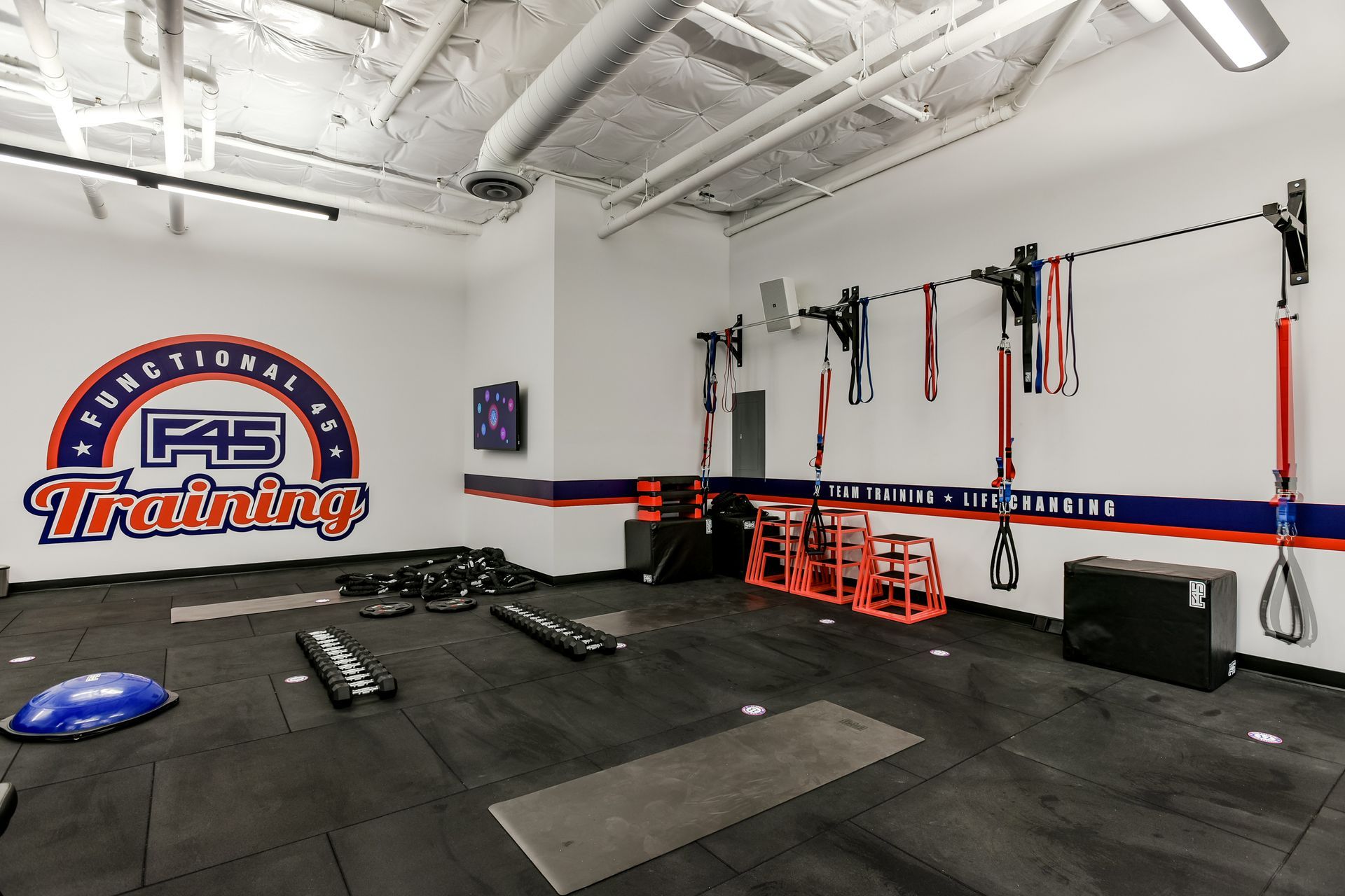Interior of F45 Training gym with equipment. White walls with blue and red accents.