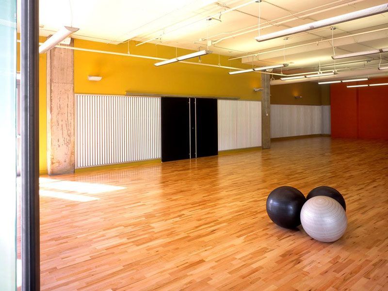 Empty studio with wood floor, exercise balls, and colored walls.