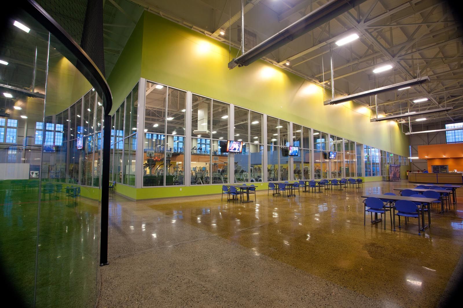 Indoor recreation space with glass walls, cafe tables, and colorful accents.