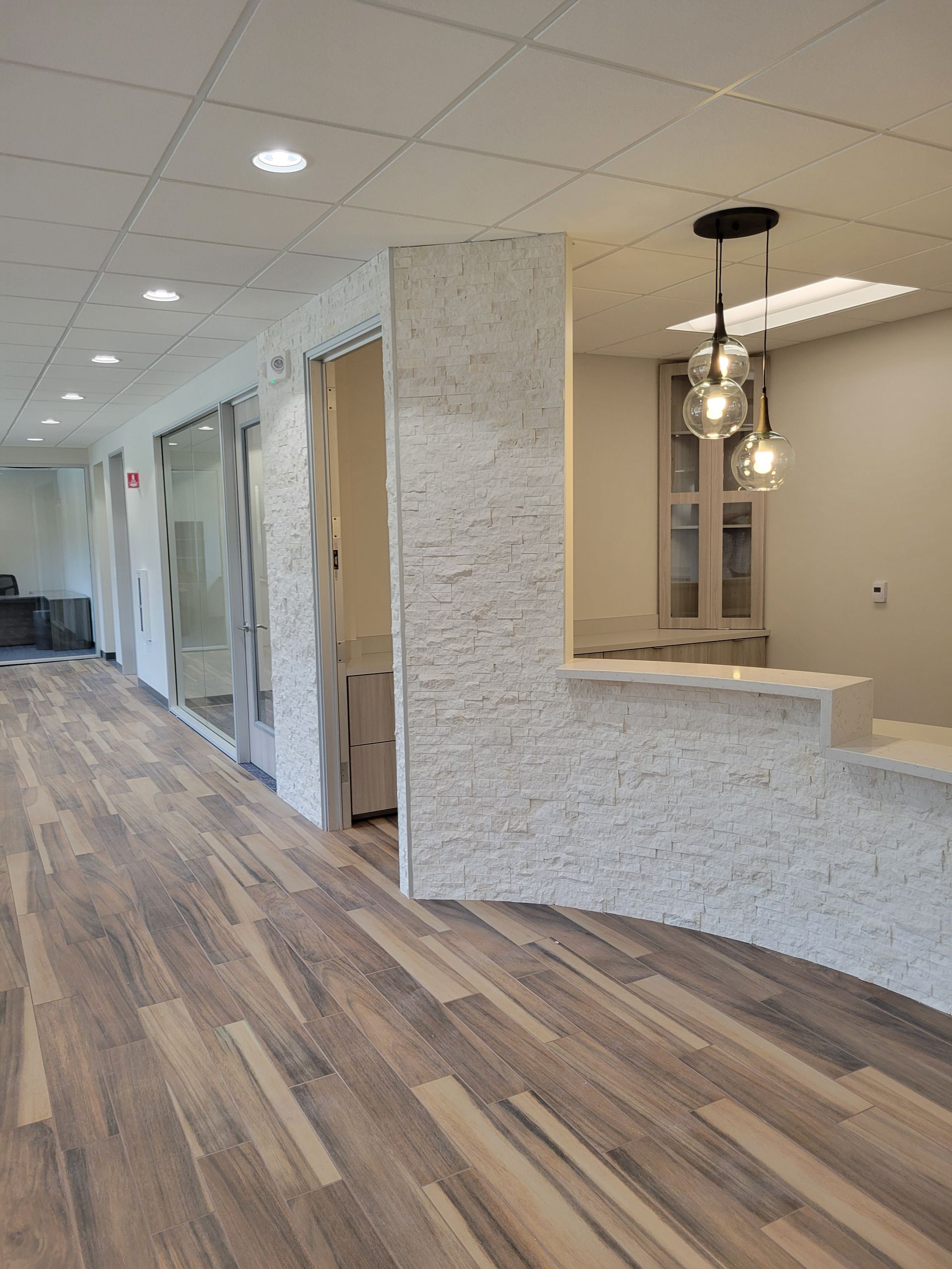 Hallway with wood-look floor, textured white walls, recessed lighting, and a pendant light fixture.