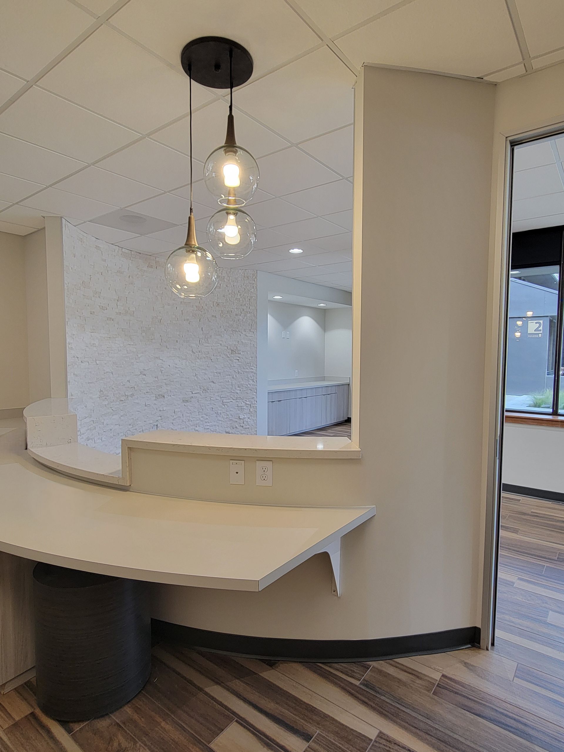 Reception area with curved countertop, pendant lights, and textured wall.