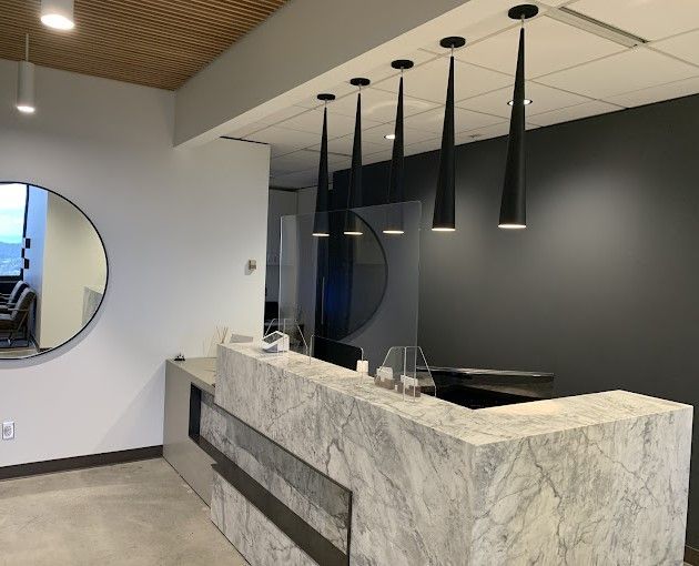 Reception area with marble counter, round mirror, and black pendant lights.