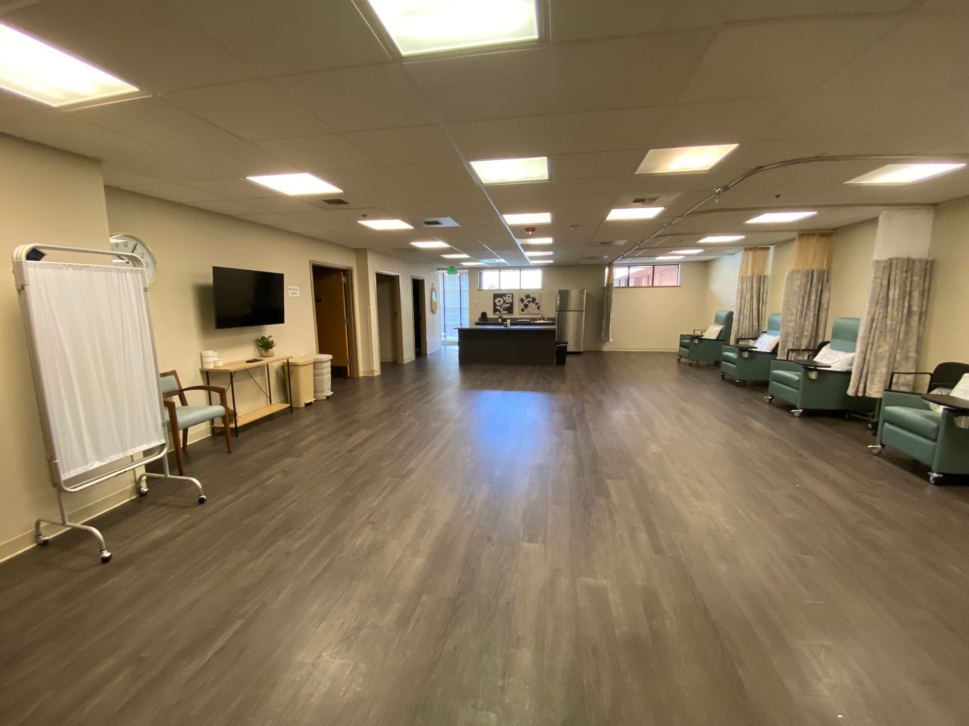 Spacious medical waiting room with chairs, privacy curtains, and a whiteboard.