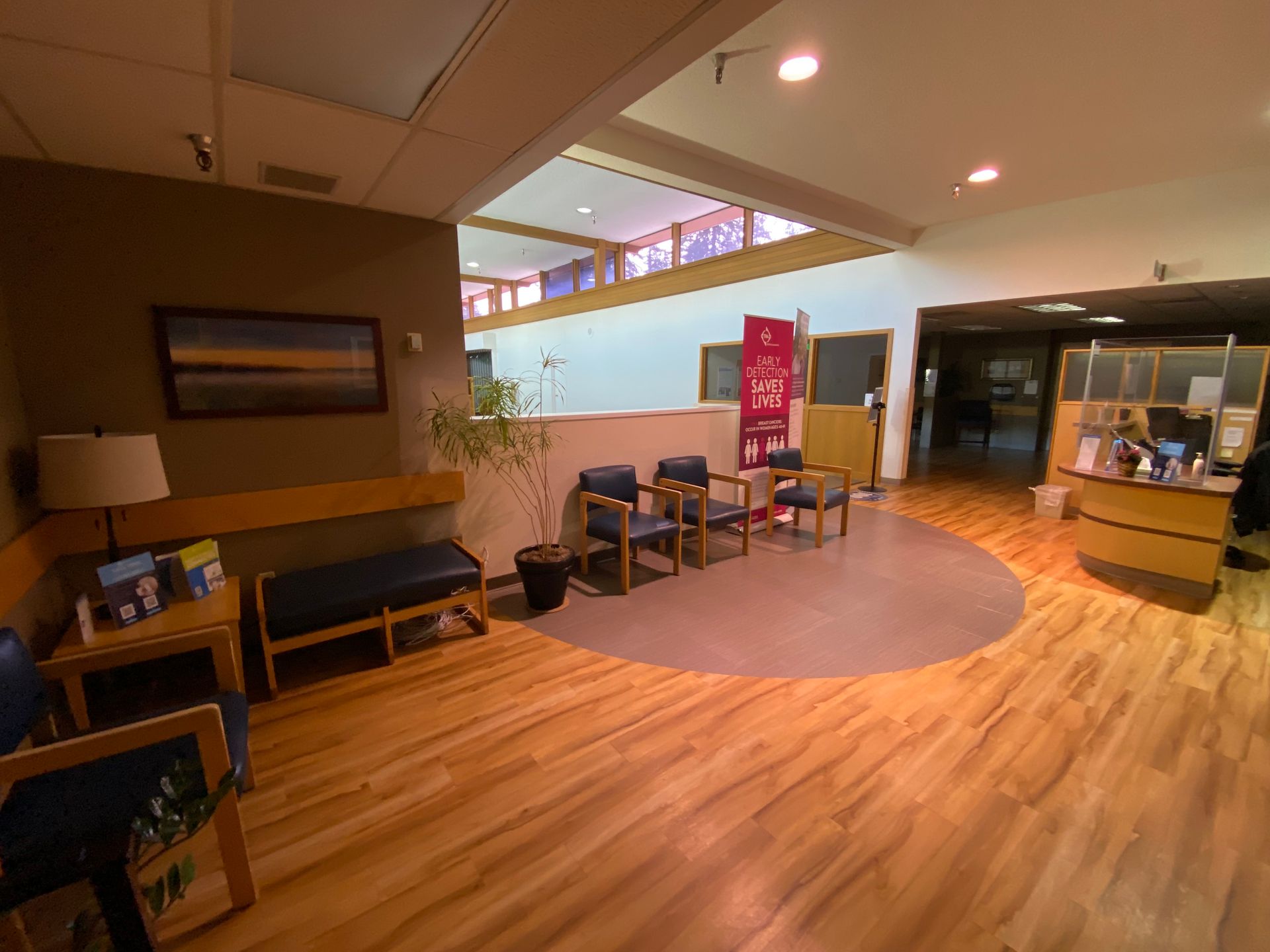 Waiting room with wood floors, seating, and a reception desk.