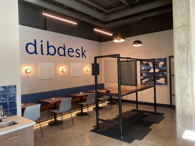 Interior of dibdesk co-working space with seating, tables, and a branded wall.