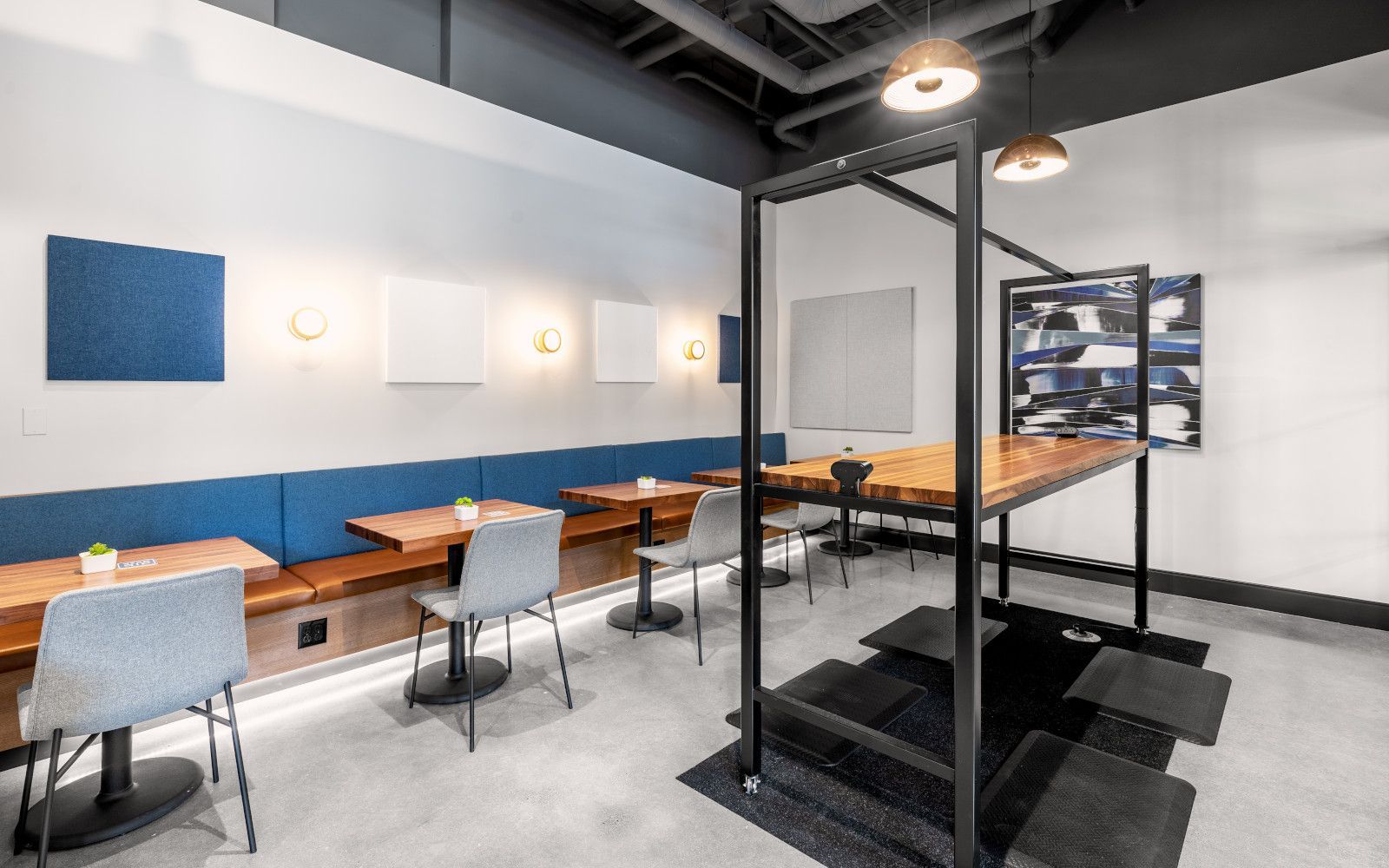 Interior shot of a modern cafe with tables, built-in benches, and pendant lights. Blue and white decor.