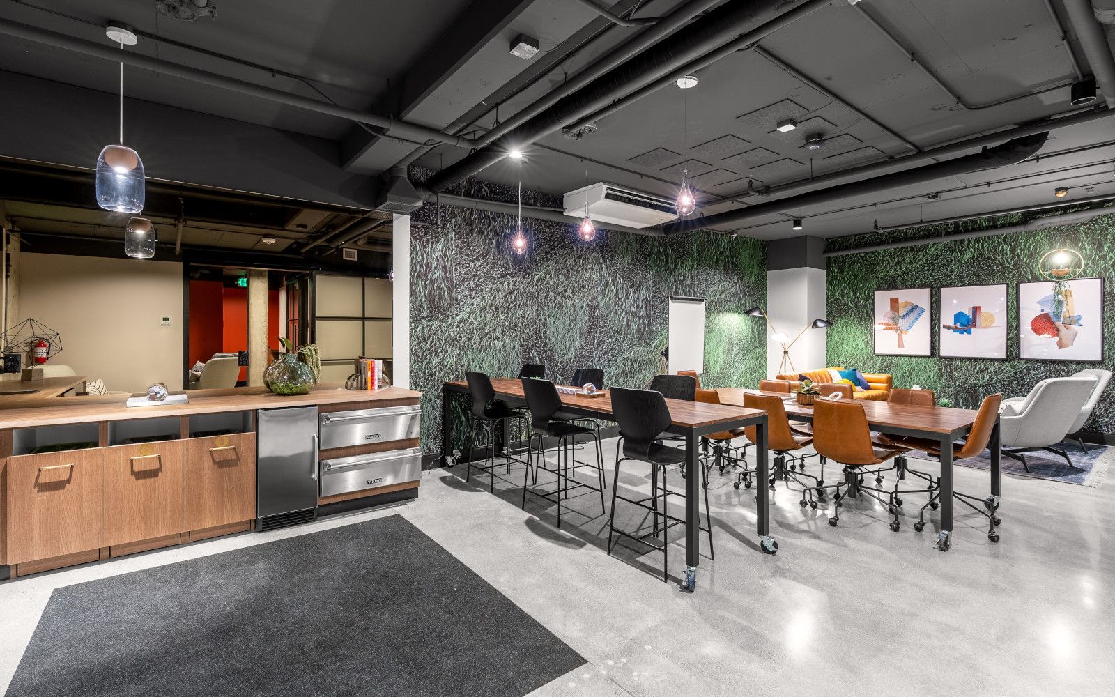 Modern office meeting room with tables, chairs, bar area, and decorative wall.