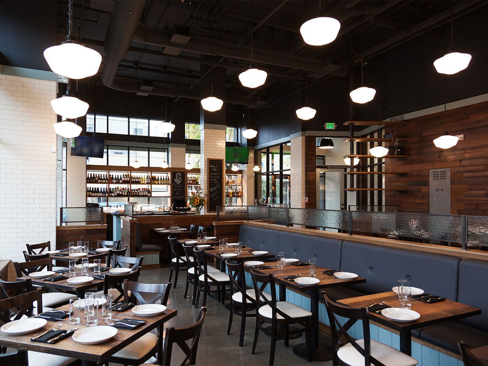 Restaurant interior with tables set for dining, pendant lights, and a bar area.
