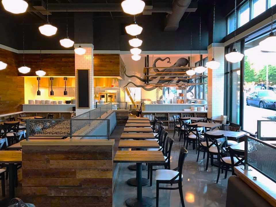 Restaurant interior with wood accents, metal tables, and an octopus mural.