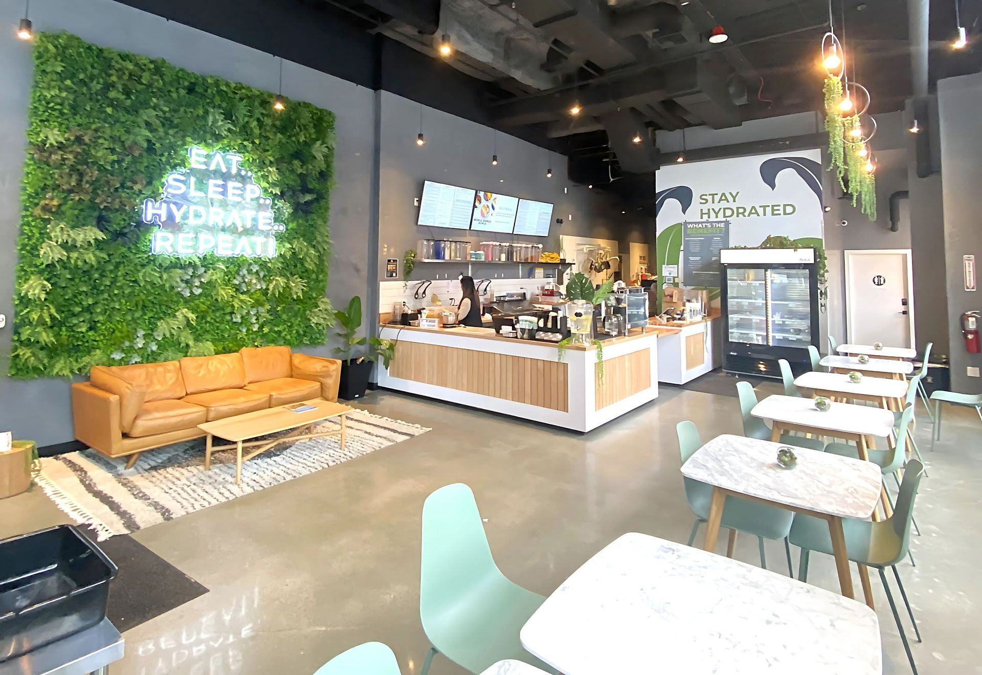 Interior of a cafe with a green wall, seating, and a counter with a barista.