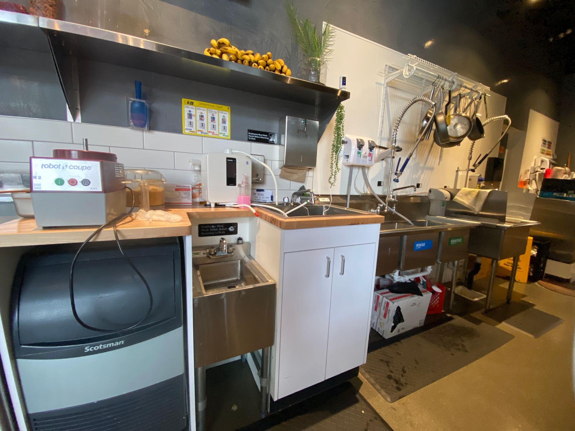 Kitchen workspace with sink, ice machine, and stainless steel equipment.