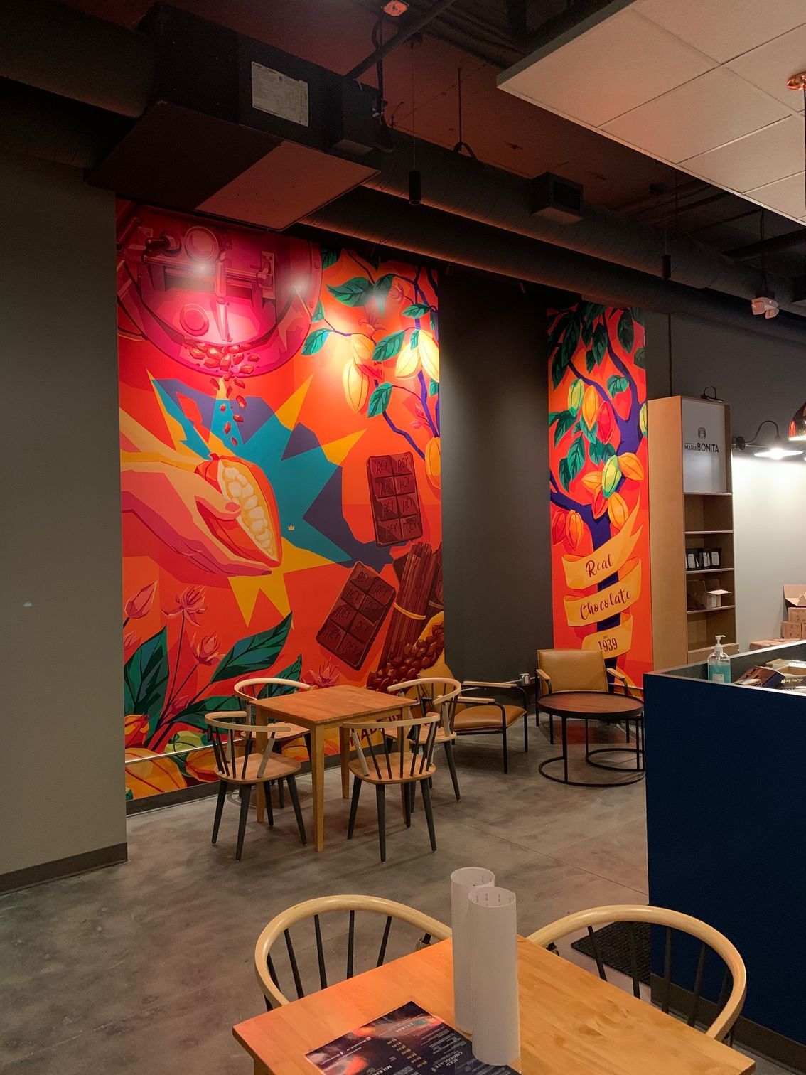 Colorful cafe interior with murals, tables, and chairs.