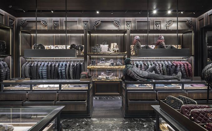 Dark, ornate clothing store interior with jackets on racks, display cases, and mannequins.