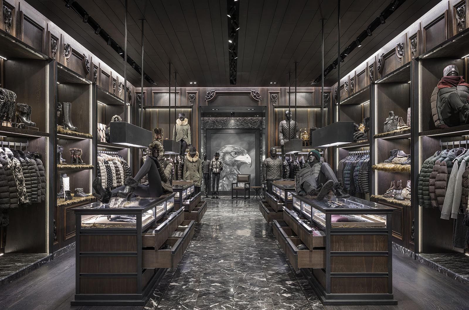 Upscale retail store interior with dark wood displays, clothing, and marble floor.