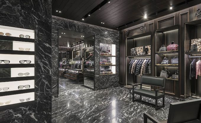 Luxury retail interior with dark marble walls and display shelves filled with merchandise.