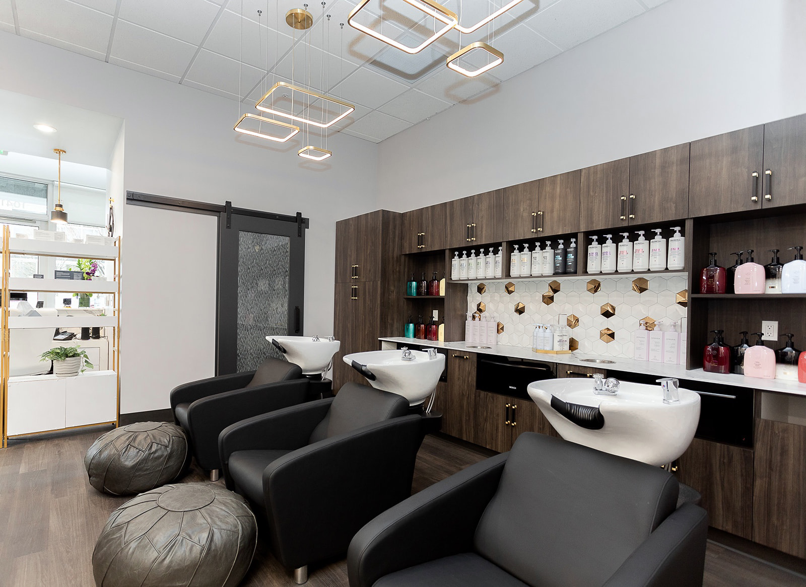 Salon with black chairs, sinks, wooden cabinets, and decorative lighting.