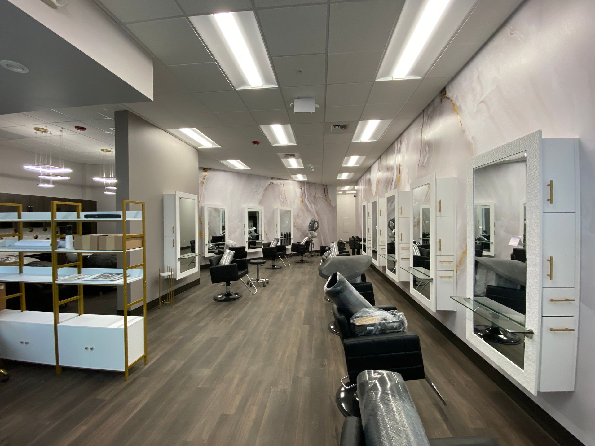 Hair salon interior with mirrors, chairs, and wood flooring.