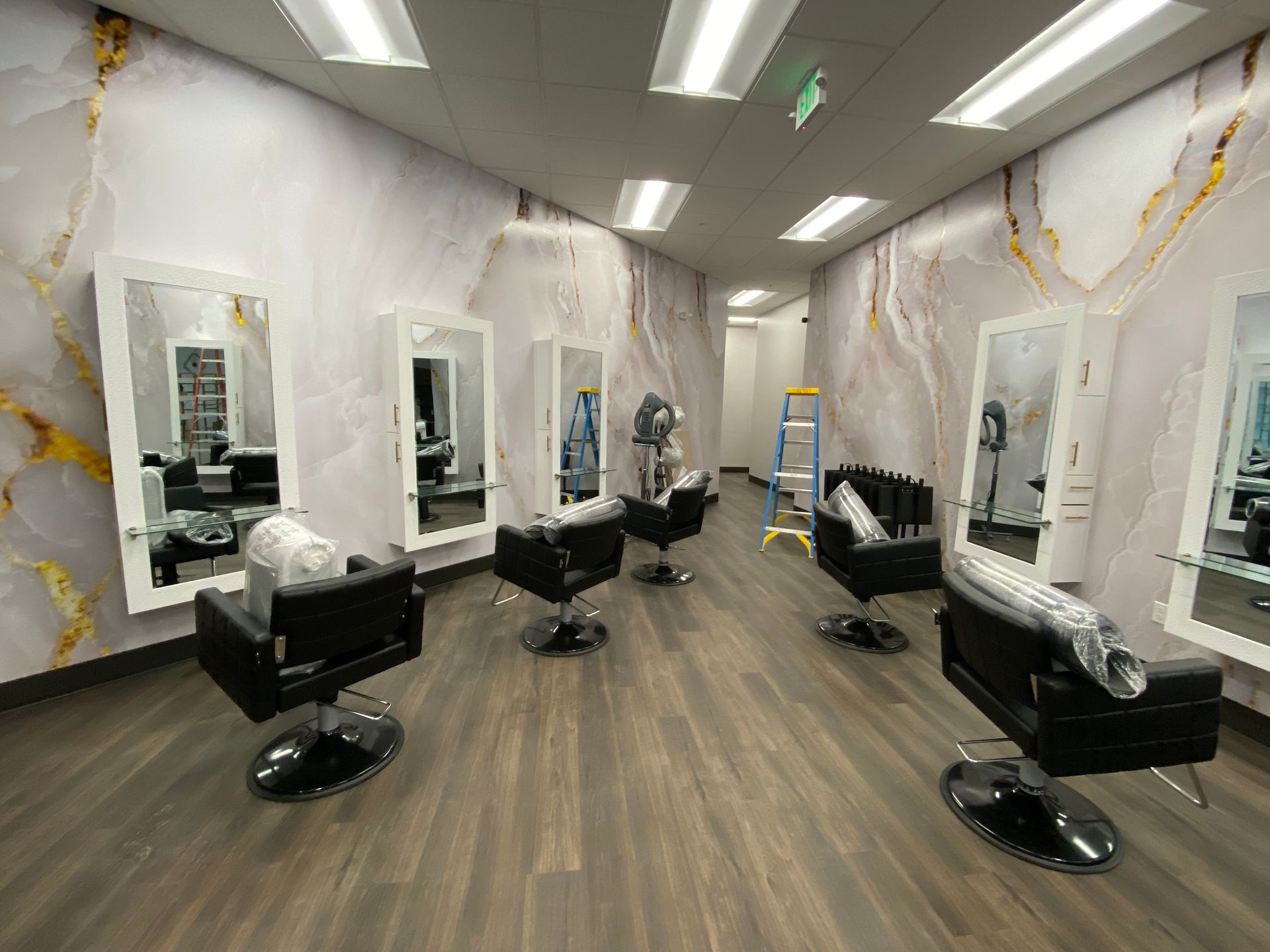 Salon interior with black styling chairs, mirrors, and marbled walls.