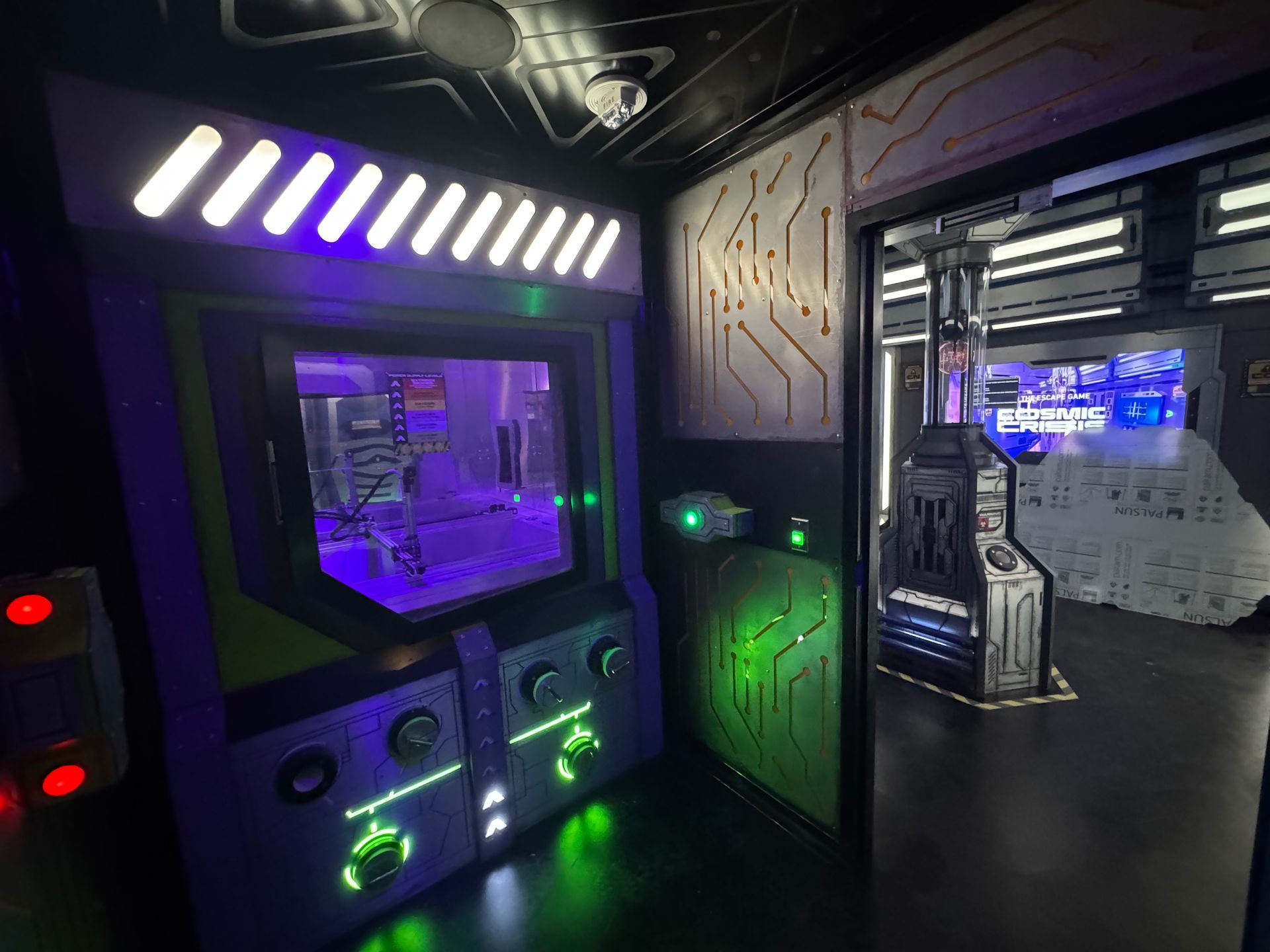 A futuristic arcade game with purple and green lights, next to an open doorway with more futuristic decor.