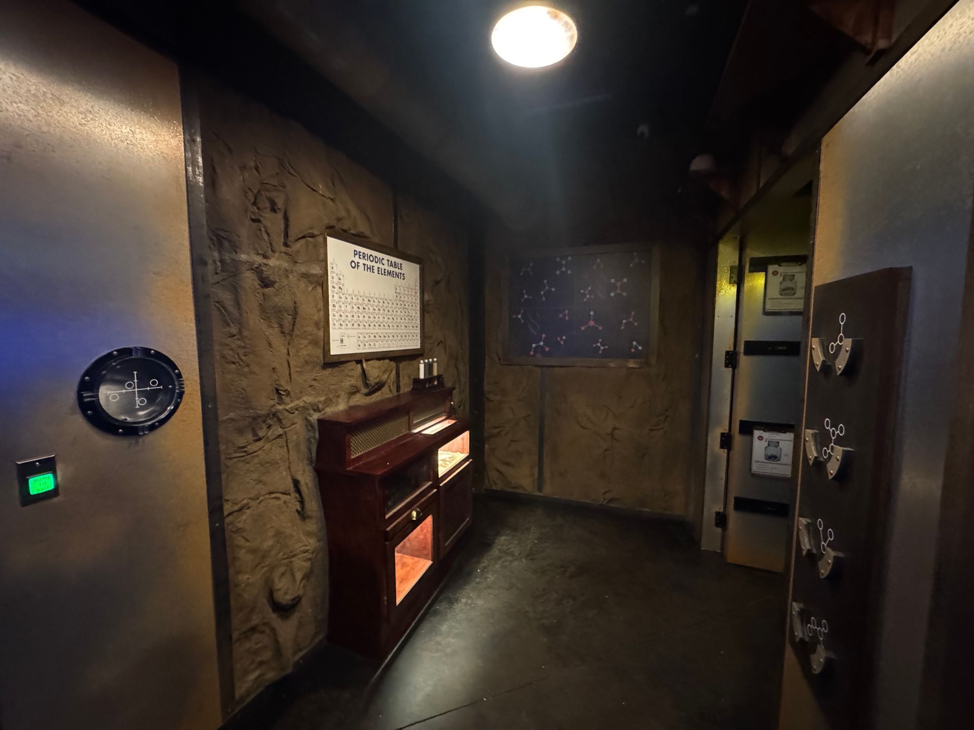 Dark room interior with stone walls, a vintage radio, and a door with buttons.