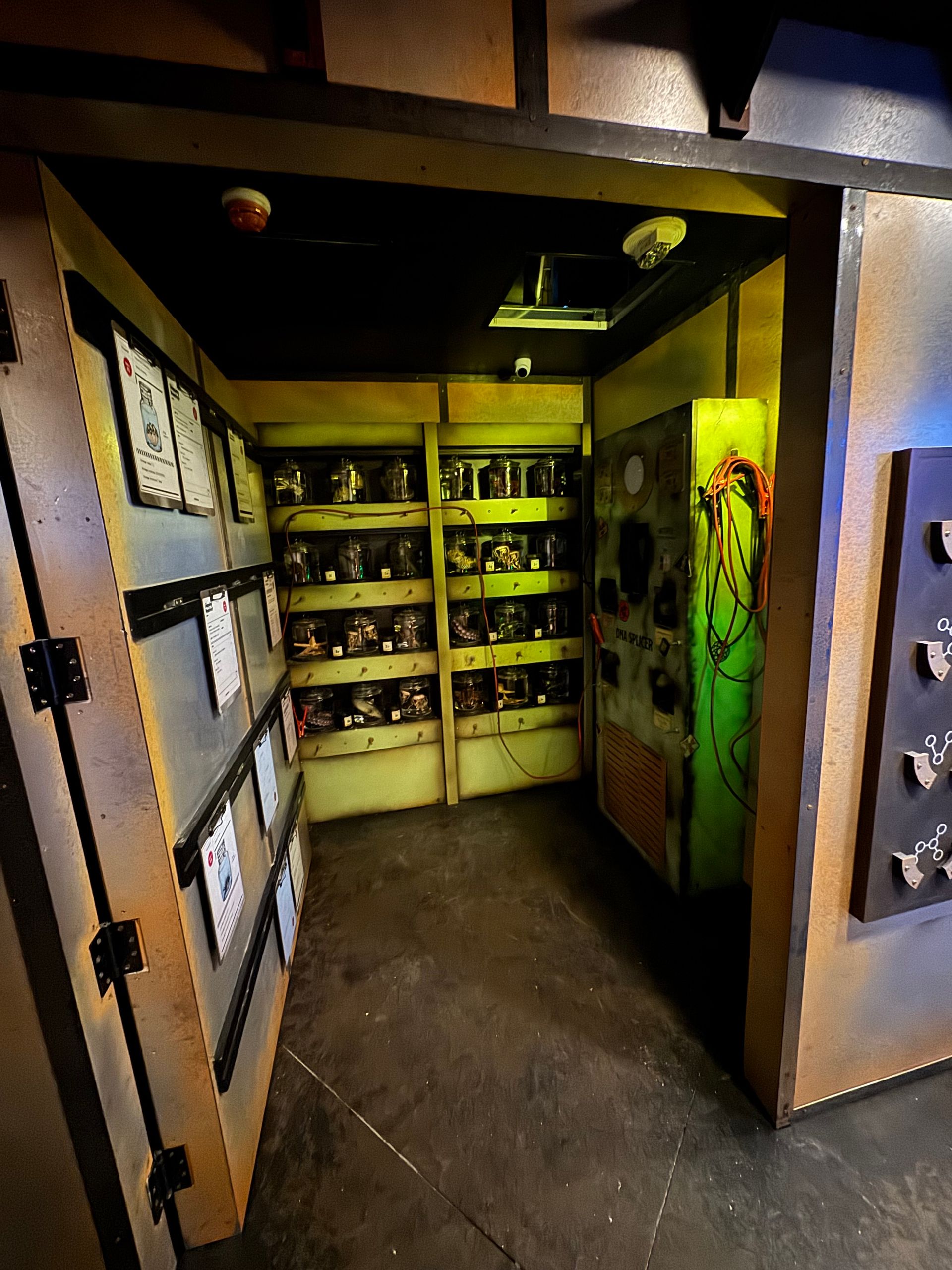 A dimly lit room with lockers and shelves containing jars. A decorated panel is visible.