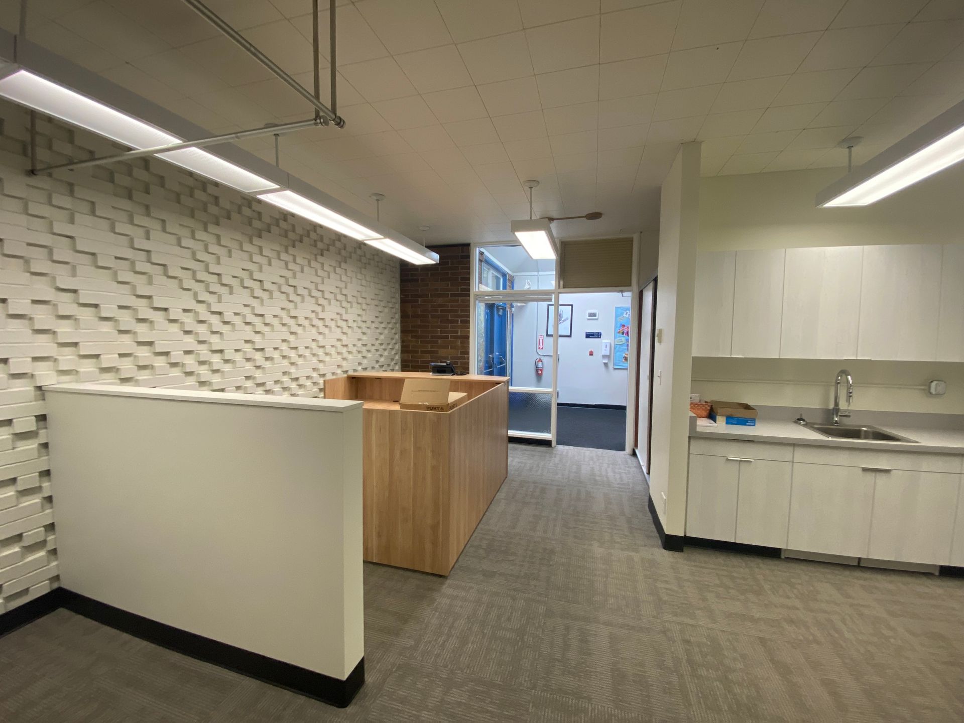 Office interior with a reception desk, patterned wall, and open doorway.