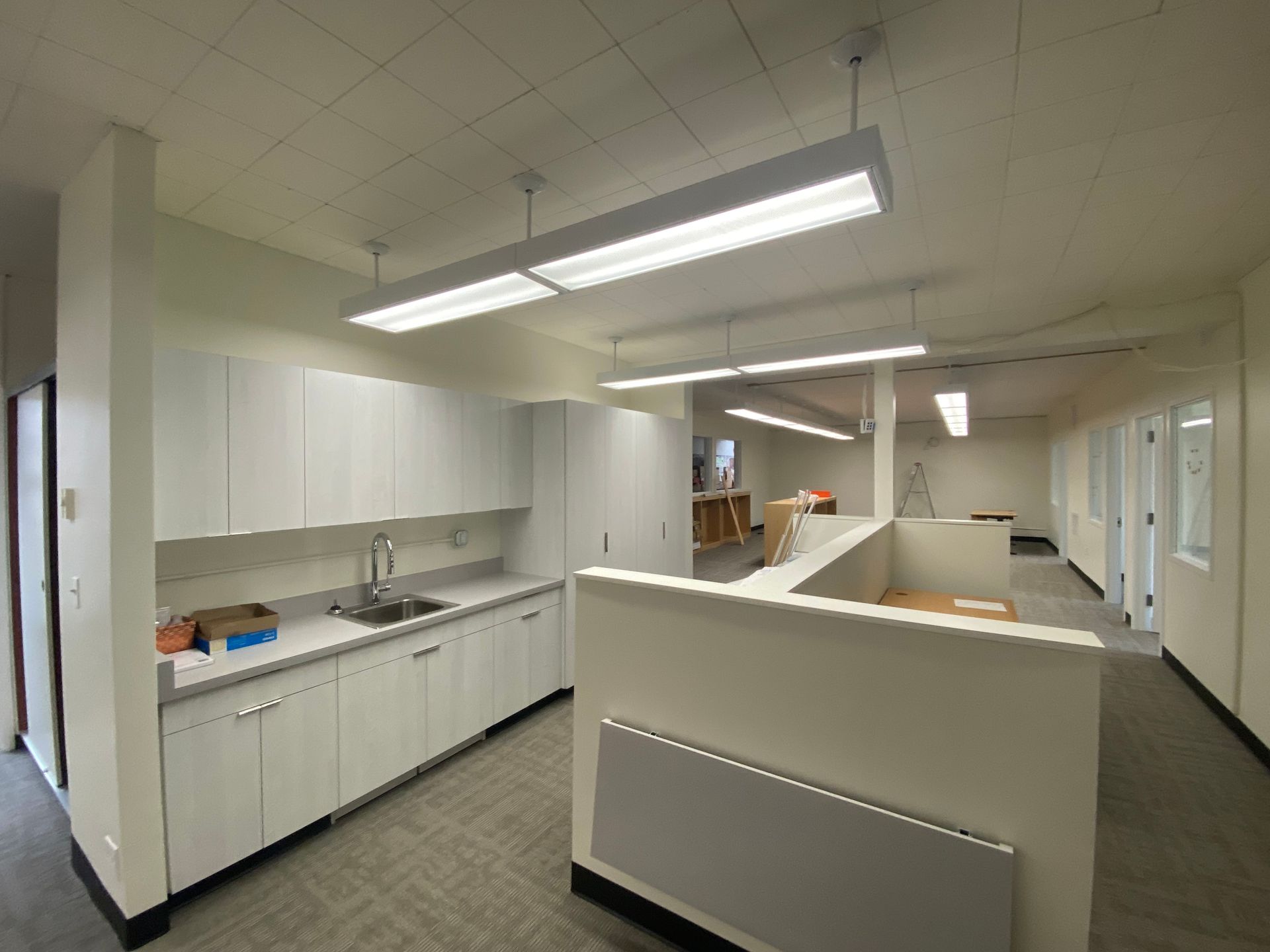 Interior office space with white cabinetry, sink, and fluorescent lighting.