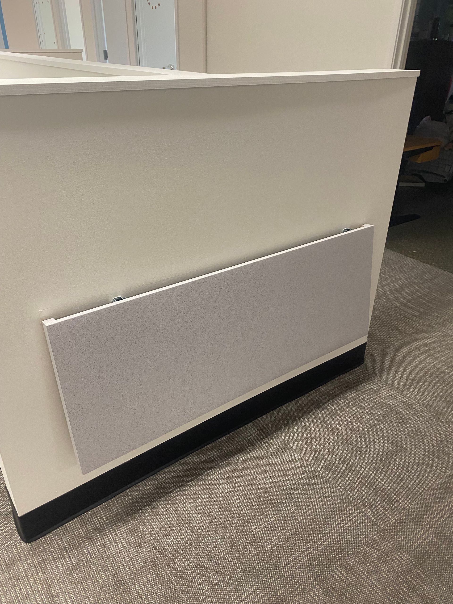 White counter with a rectangular grey panel, black base, and carpet.