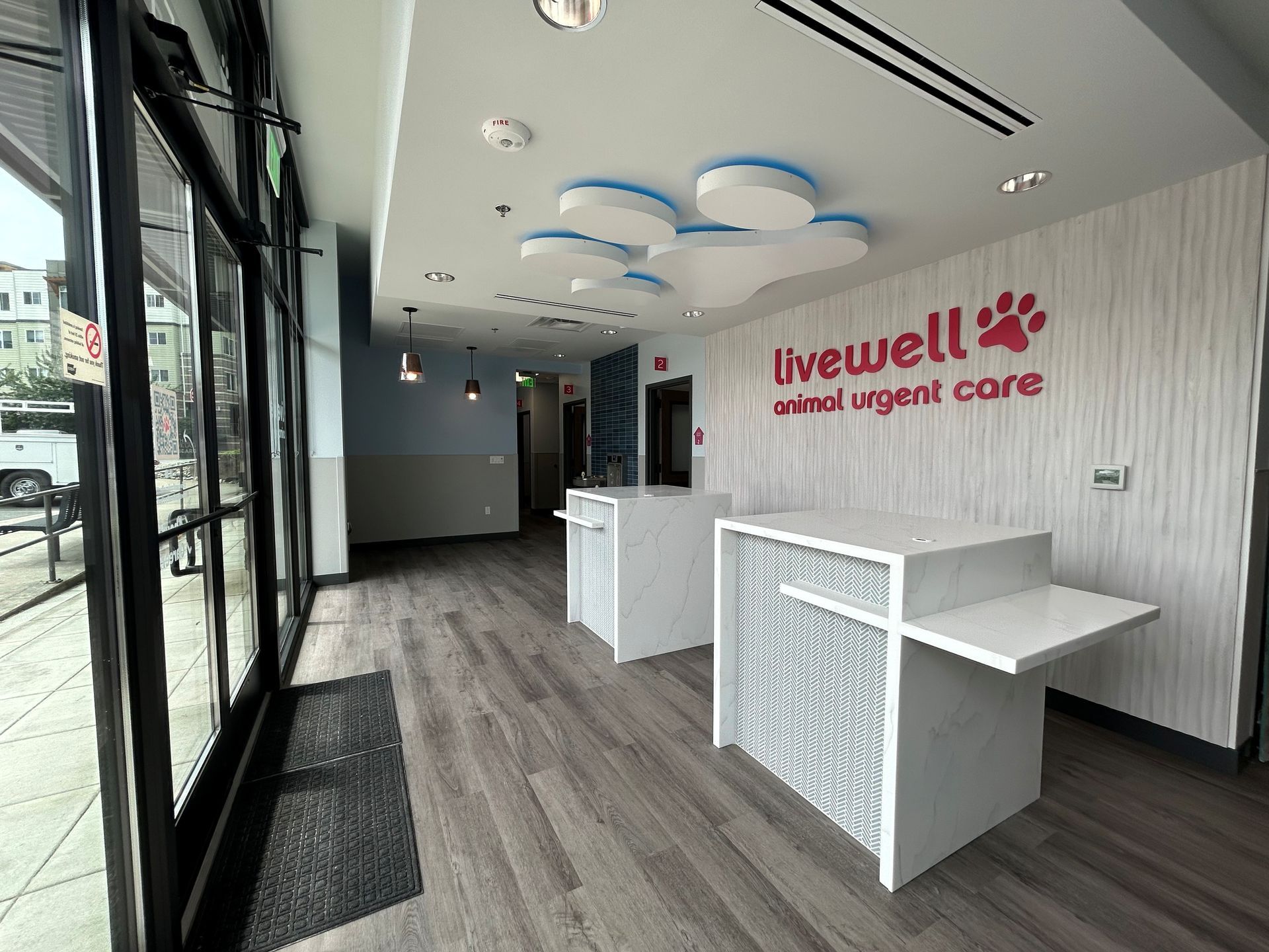 Interior of LiveWell Animal Urgent Care with reception desks and paw-shaped ceiling lights.