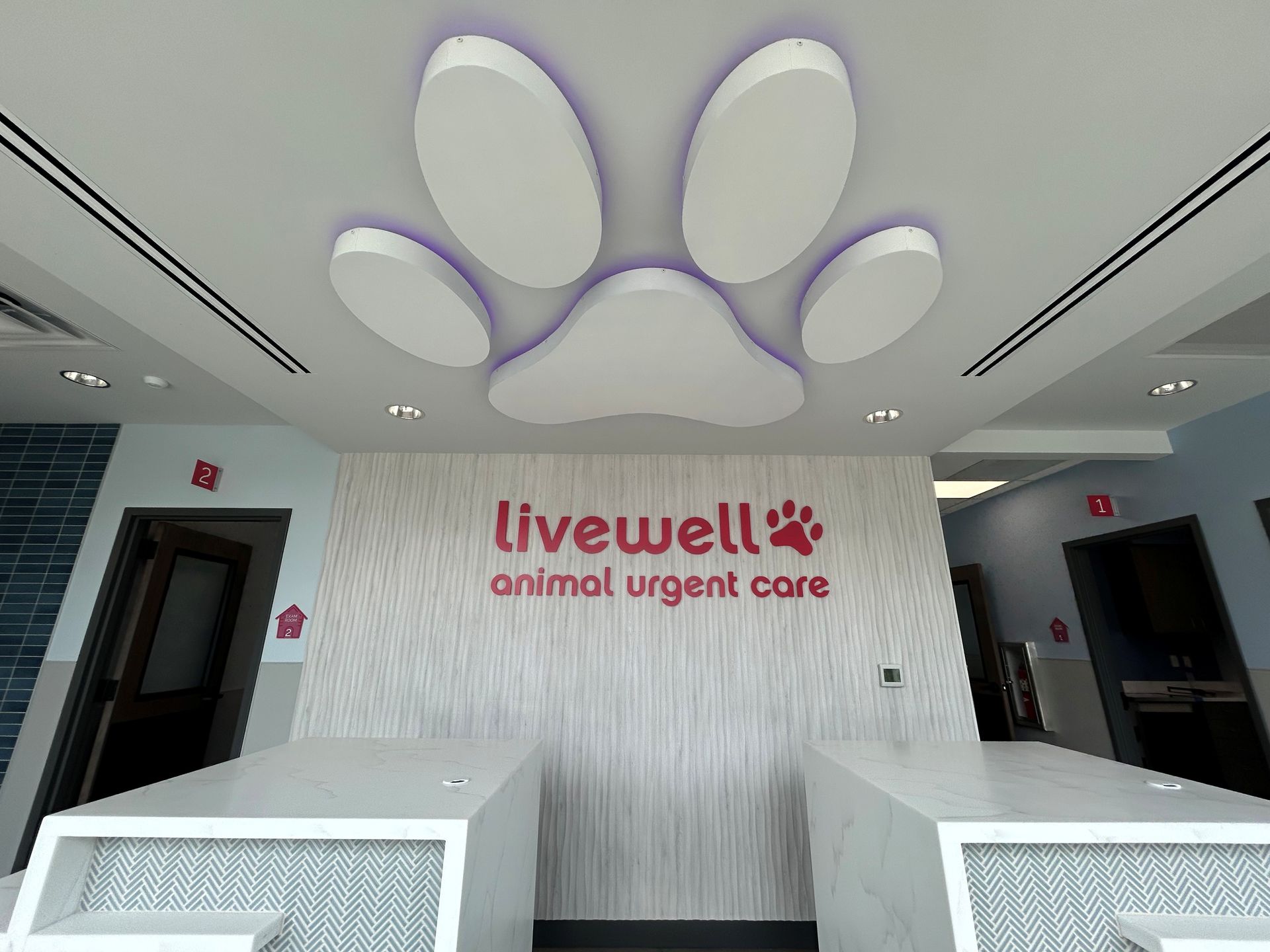 Lobby of a pet urgent care clinic with a paw print ceiling design and the clinic's logo.