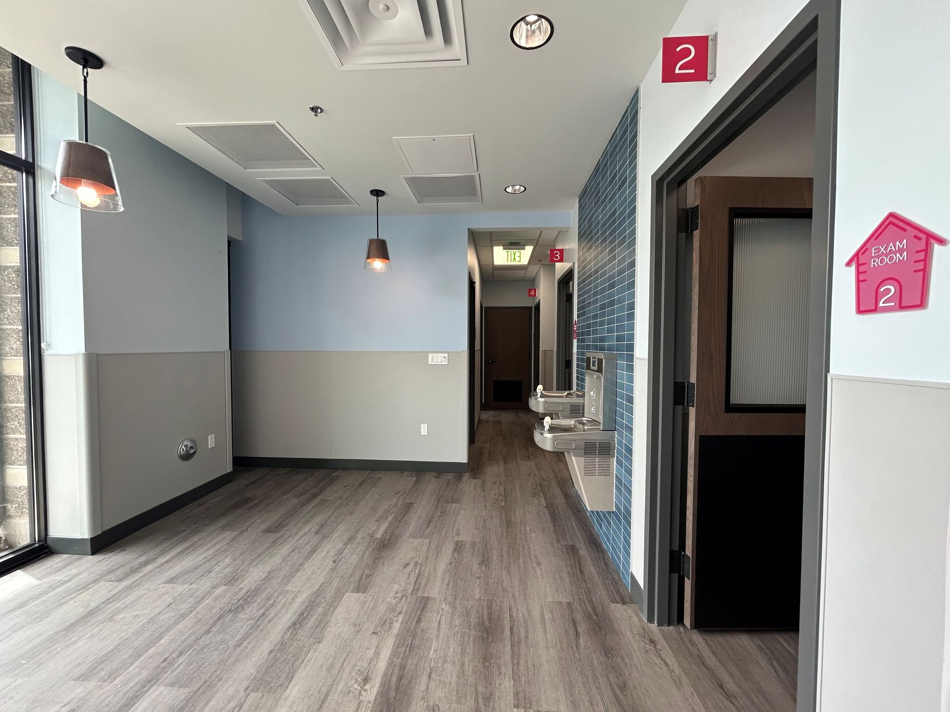Hallway with gray and blue walls, wooden floor, and doors.