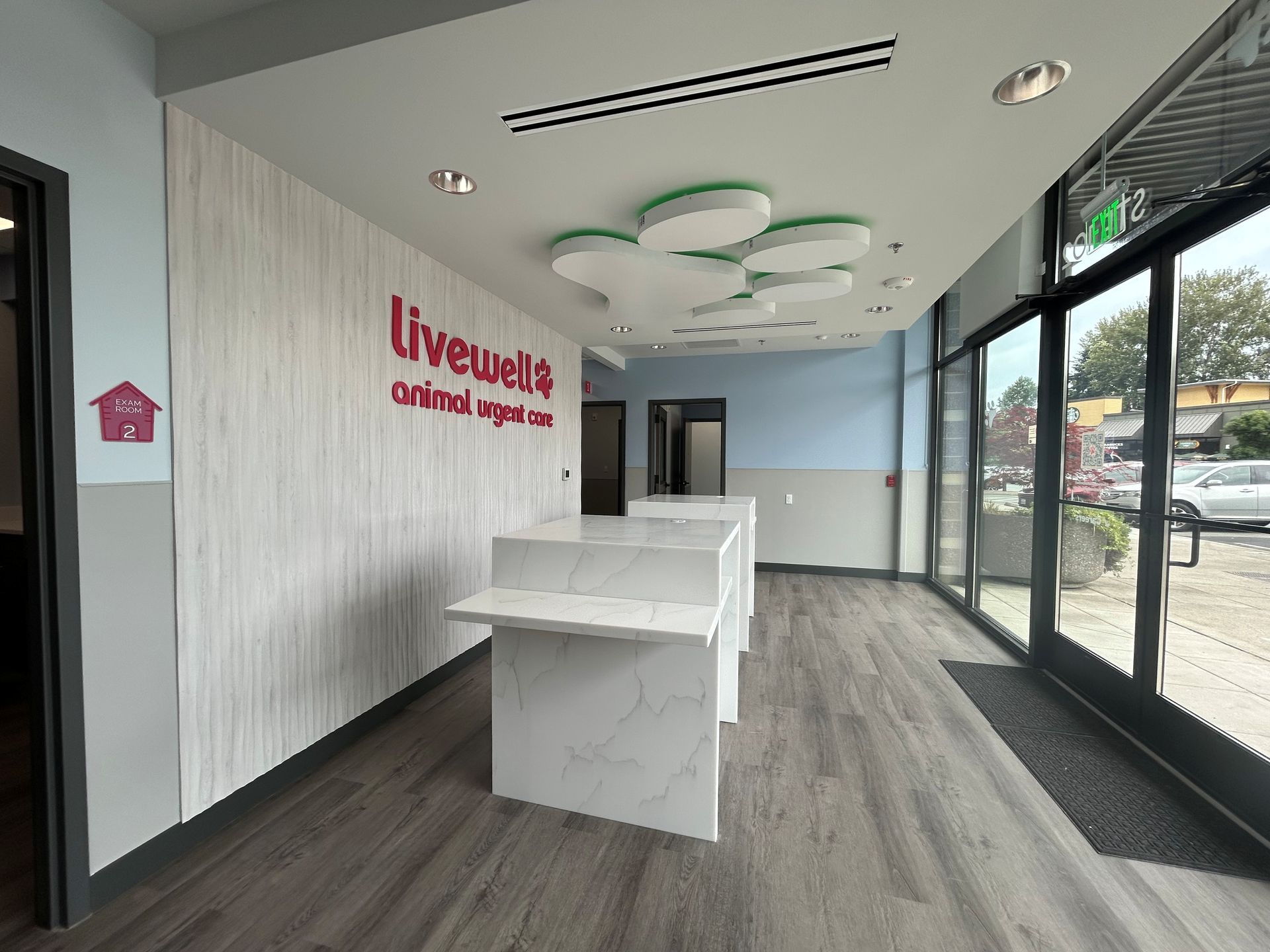 Interior of a veterinary clinic with reception desk and Livewell sign. Grey and white decor, large windows.