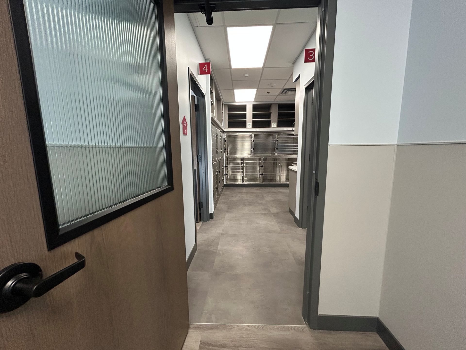 Hallway with doors, gray floor, metal cabinets visible.