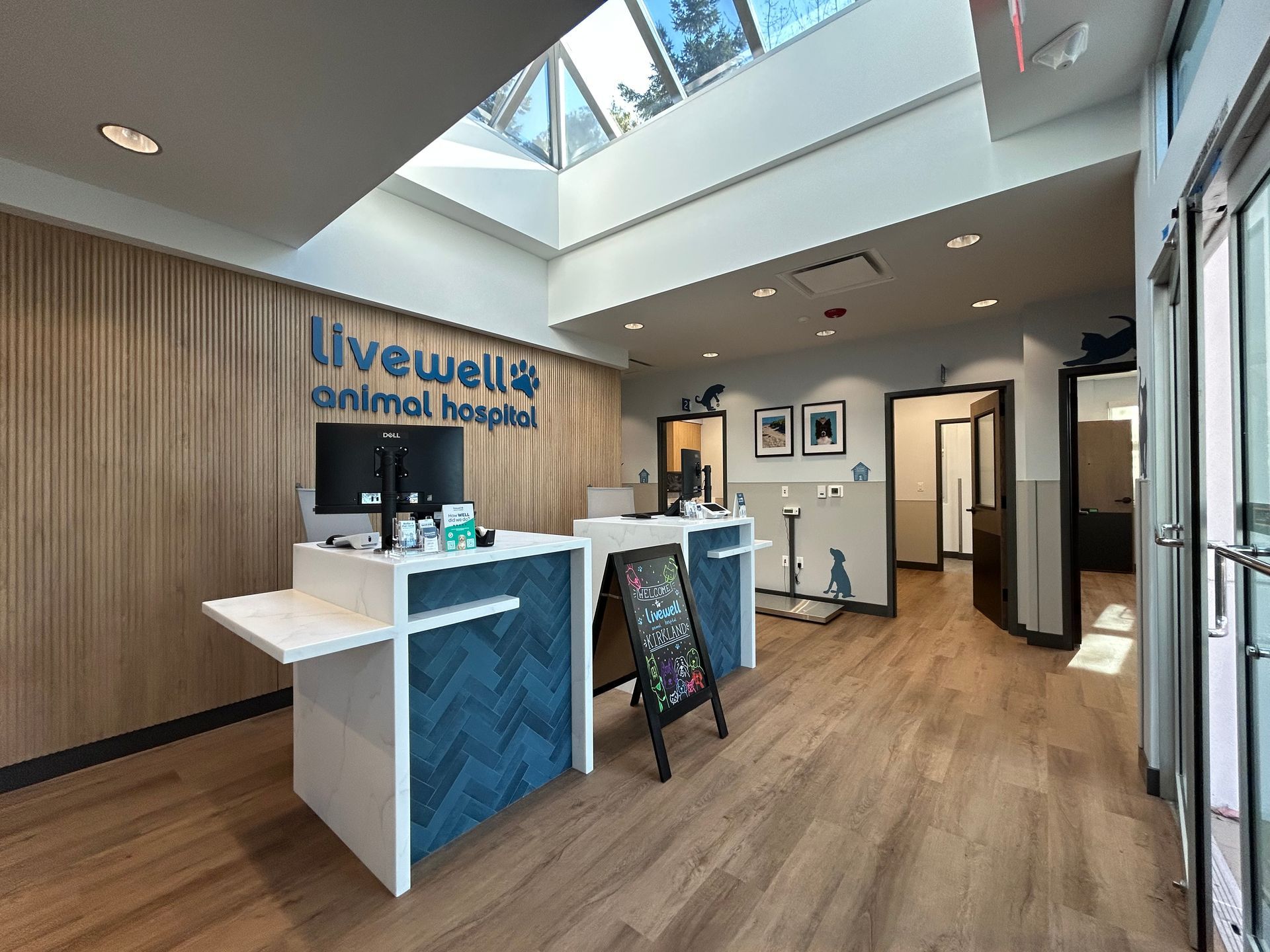 Lobby of an animal hospital with front desk, light wood floors, and waiting area. Skylight and logo visible.