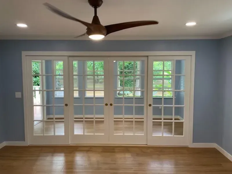 Room with blue walls, sliding glass doors, white trim, and a ceiling fan.