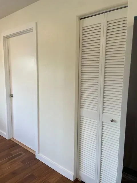 White hallway with a closed door on the left and a louvered bi-fold closet door on the right.