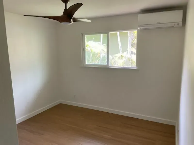 Empty room with hardwood floors, a window, and a ceiling fan.
