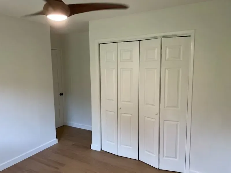 A room with closed white closet doors and a door at the back.