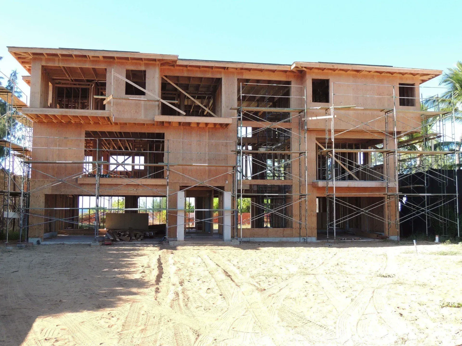 Two-story wood-framed house under construction; scaffolding surrounds; exposed framing; exterior view.