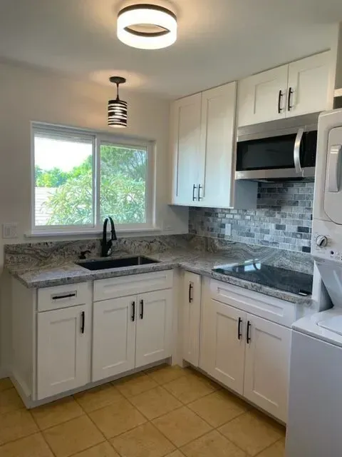 White kitchen with granite countertops, white cabinets, and stainless steel appliances.
