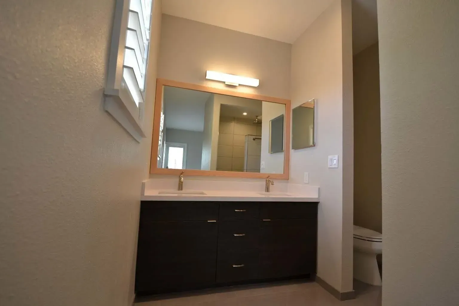 Bathroom with double vanity, large mirror, and neutral tones.