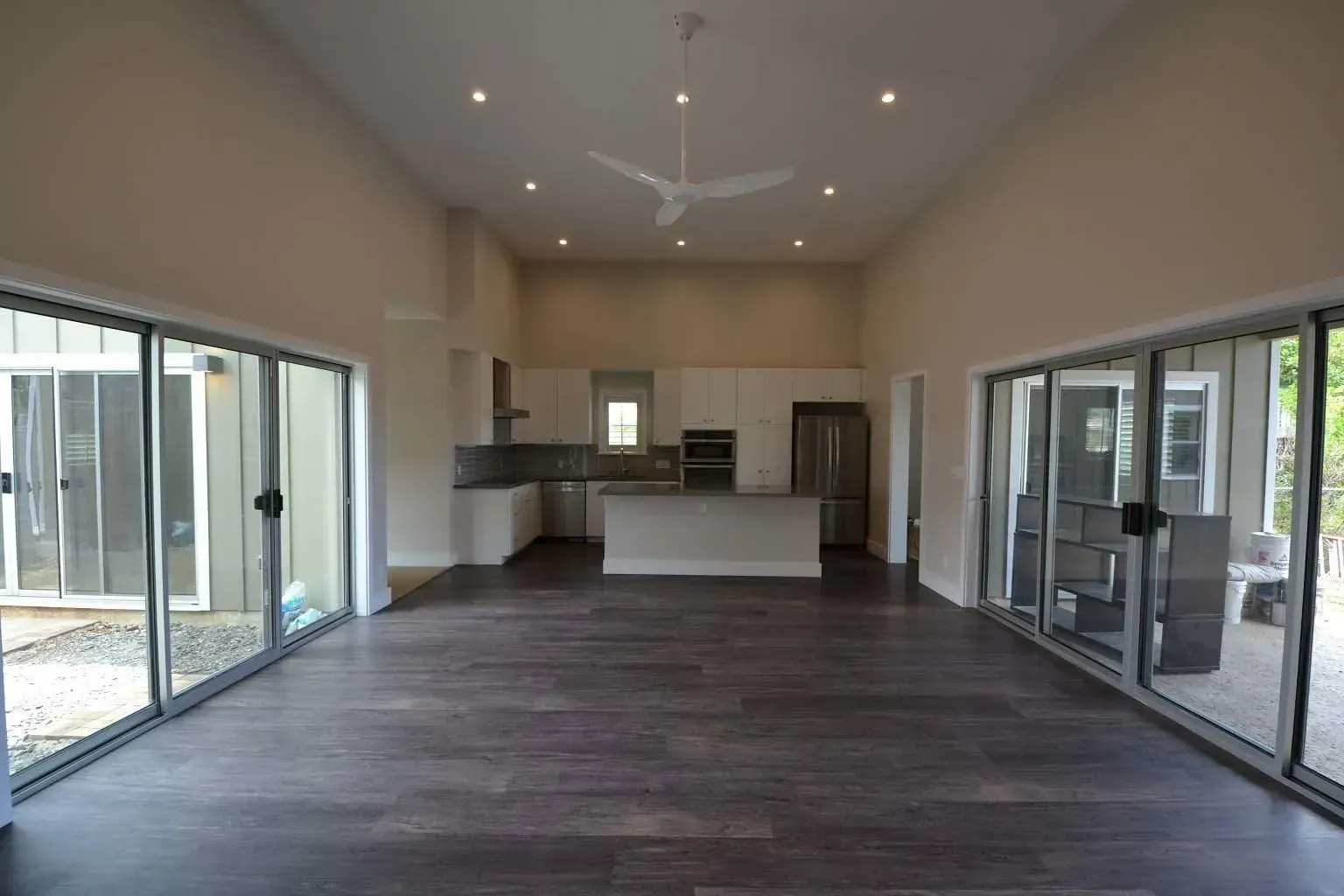 Open-concept kitchen and living area with dark wood floors, white cabinetry, and large sliding glass doors.