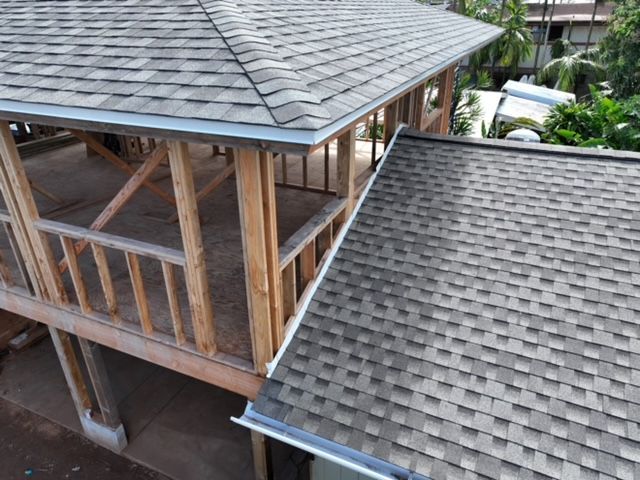 wooden gazebo with gray shingle roof next to a larger roof
